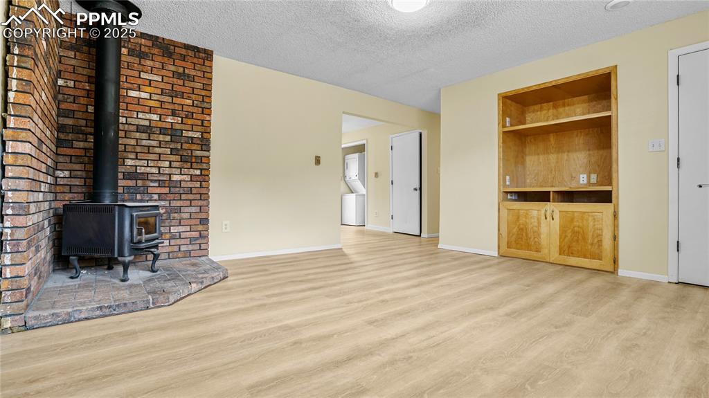 Image 4 of 25: Unfurnished living room with a wood stove, light wood-type flooring, a text