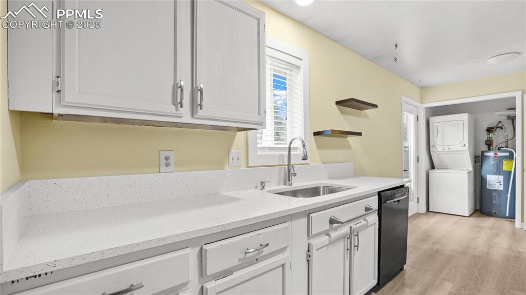Image 8 of 25: Kitchen with light stone countertops, estacked washer and dryer, electric w