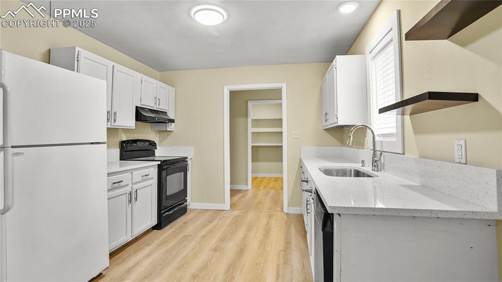 Image 9 of 25: Kitchen featuring freestanding refrigerator, black / electric stove, light