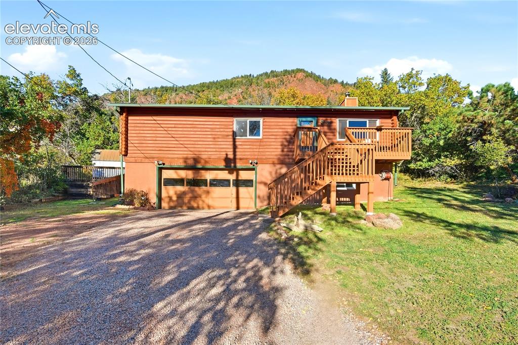 Image 1 of 34: Split-level exterior with a two-car garage, wood siding, and an upper-level