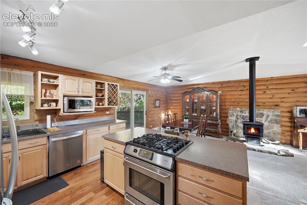 Image 12 of 34: Wood-paneled kitchen with stainless steel appliances and wood-finish floori