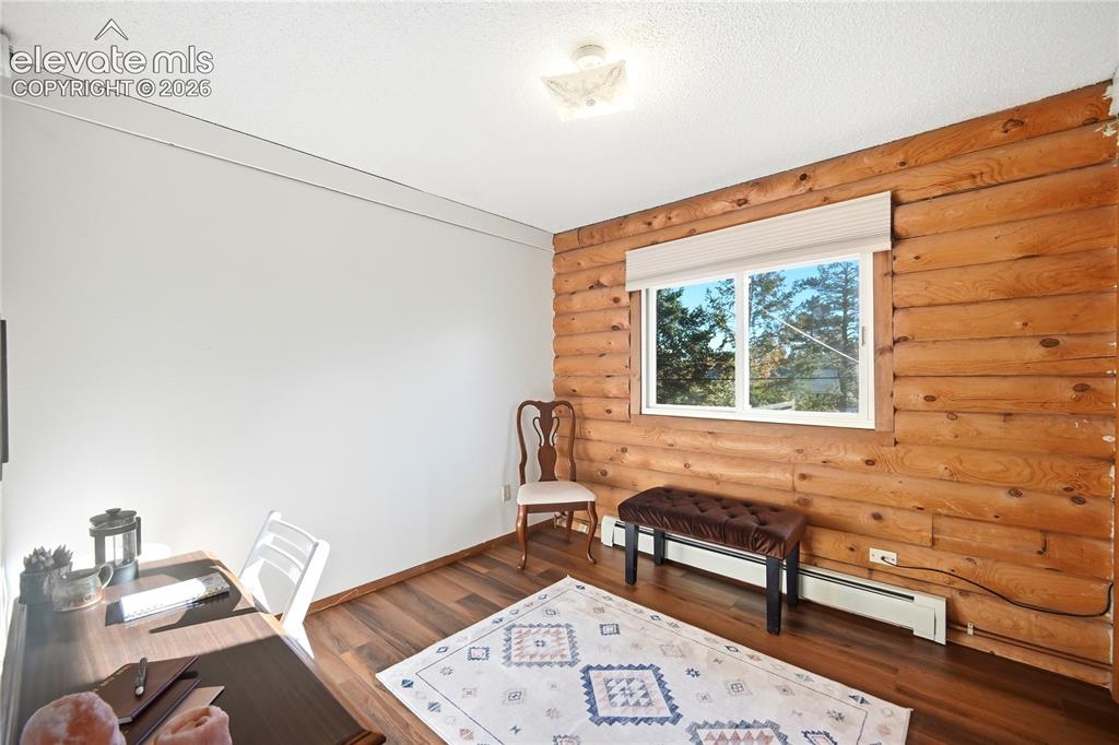 Image 13 of 34: Wood-finish flooring, log wall feature, white painted wall, white framed wi