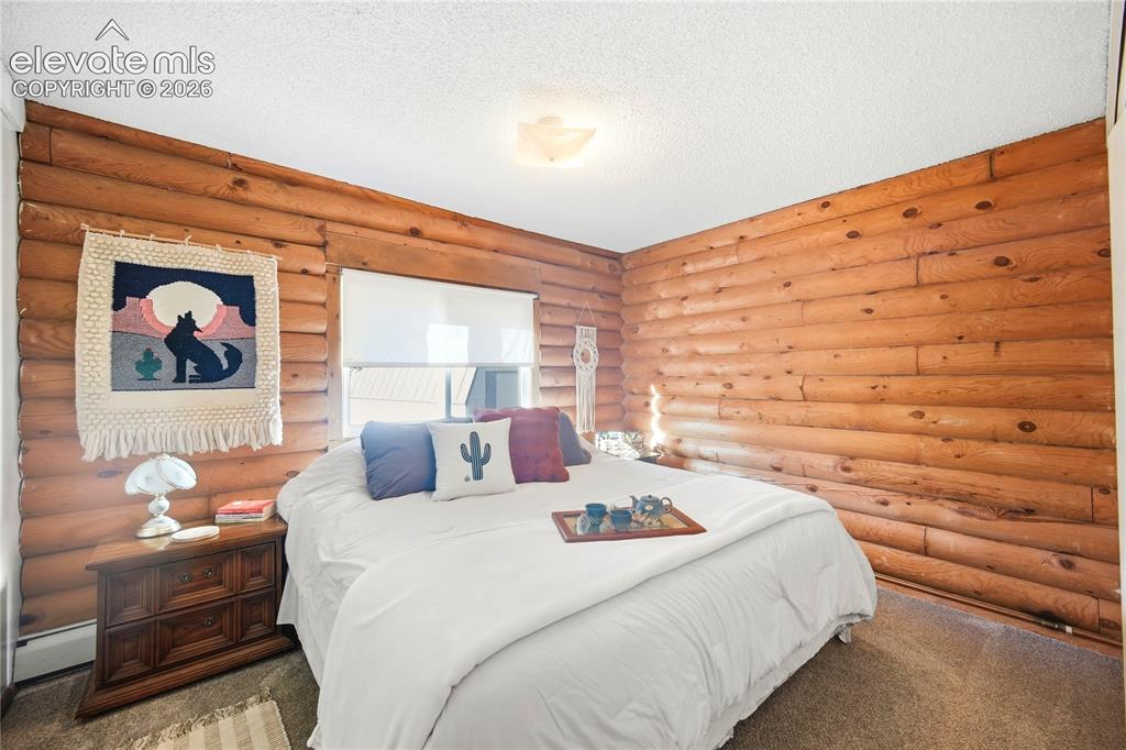 Image 16 of 34: Log wall construction with a window featuring a roller shade