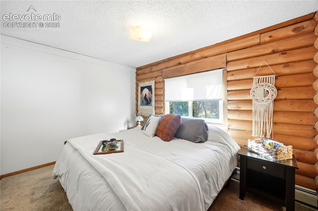 Image 17 of 34: Log-finish wall paneling, white painted walls, and textured ceiling