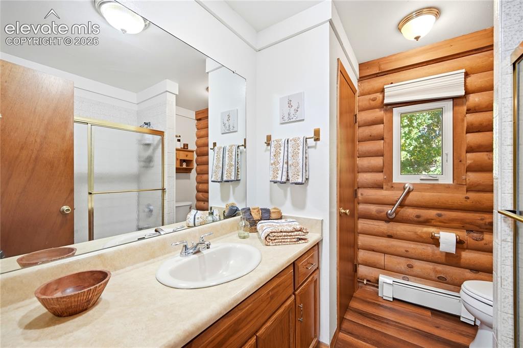 Image 18 of 34: Vanity with an integrated sink, wood-finish flooring, wood cabinetry, and a