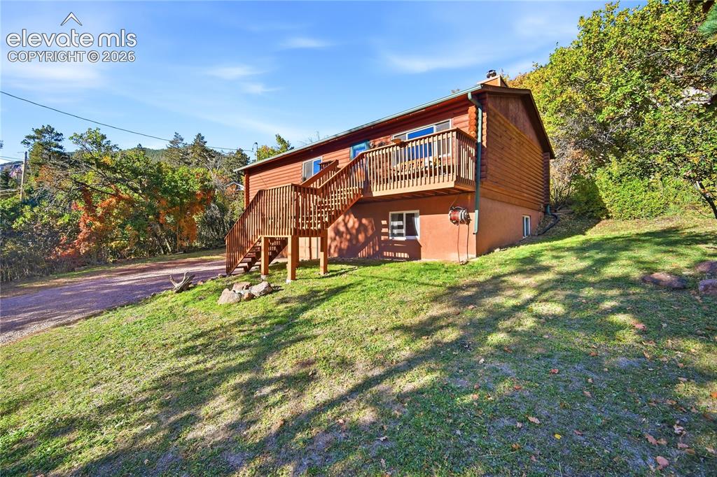Image 2 of 34: Wood-sided exterior with a natural wood deck and exterior staircase