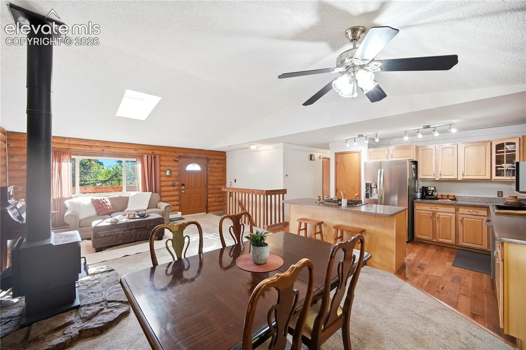 Image 27 of 34: Vaulted ceilings with a skylight, wood-paneled walls, a built-in wood-burni