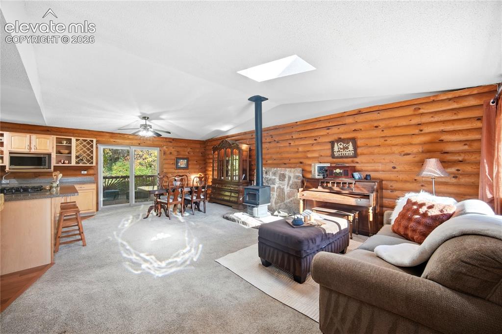 Image 3 of 34: Open-concept living area featuring wood-paneled walls, a skylight, and a bu