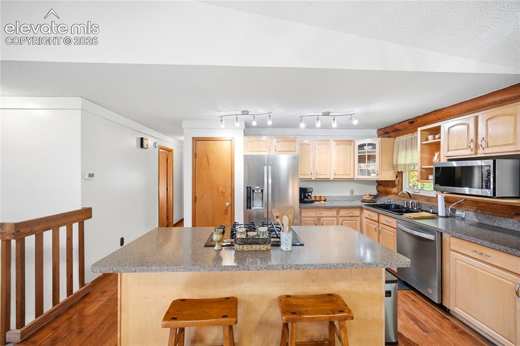 Image 8 of 34: Kitchen featuring a central island with a cooktop, wood-finish flooring, li
