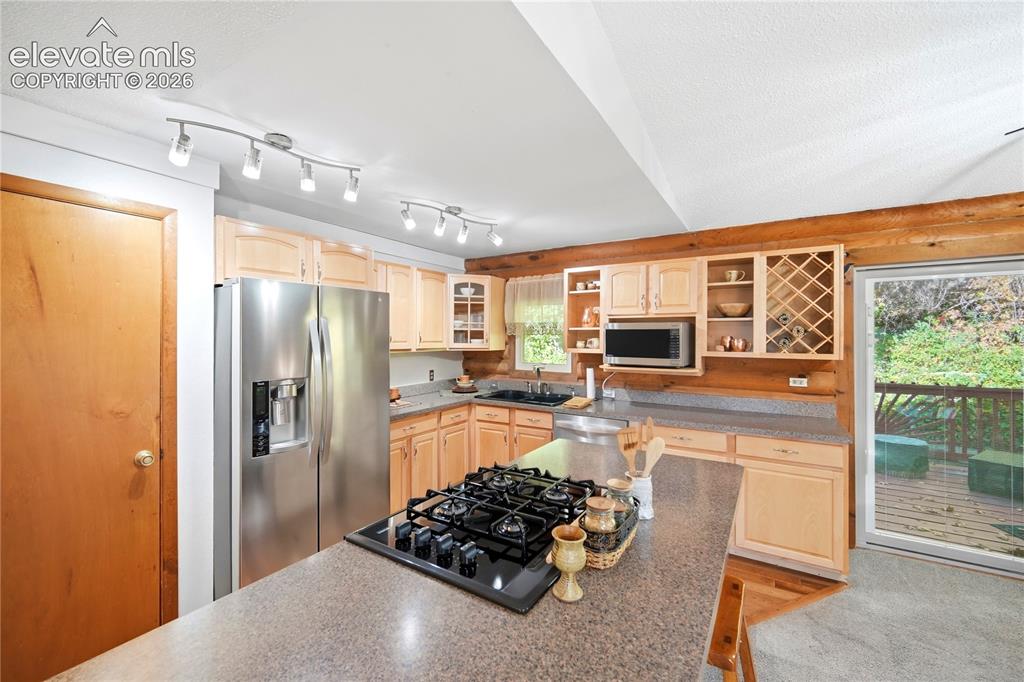Image 9 of 34: Kitchen featuring light wood cabinetry, stainless steel refrigerator, built