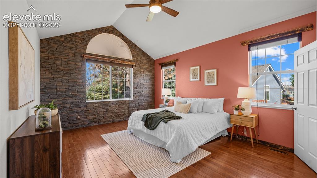 Image 12 of 43: Vaulted ceiling with wood-finish fan, stone-accent wall, arched transom win