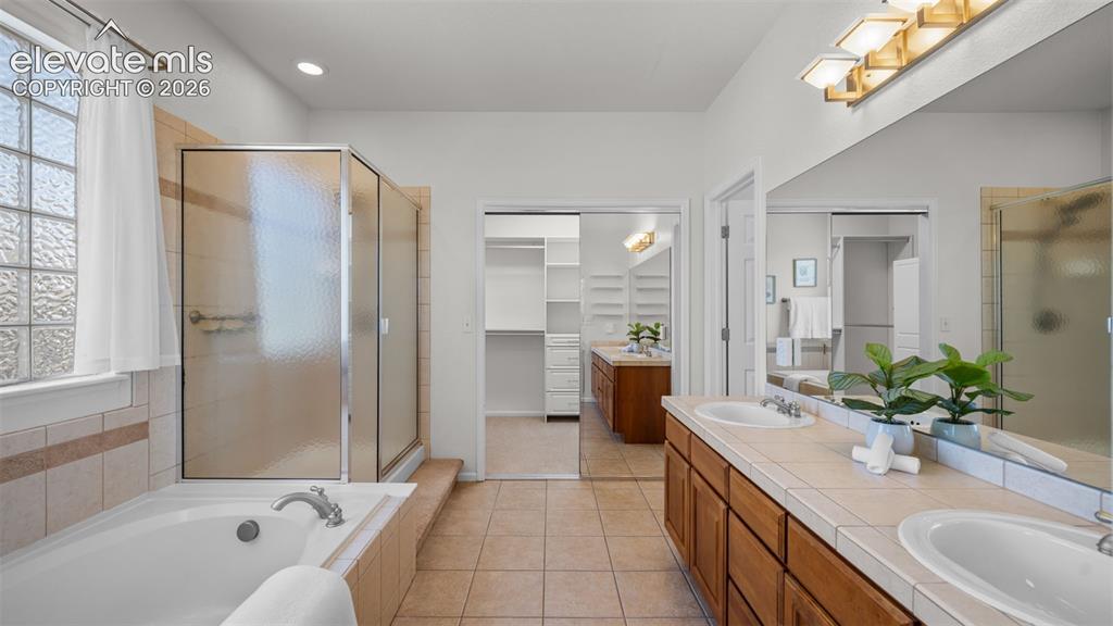 Image 14 of 43: Spacious bathroom featuring a dual vanity with tiled countertop, an enclose