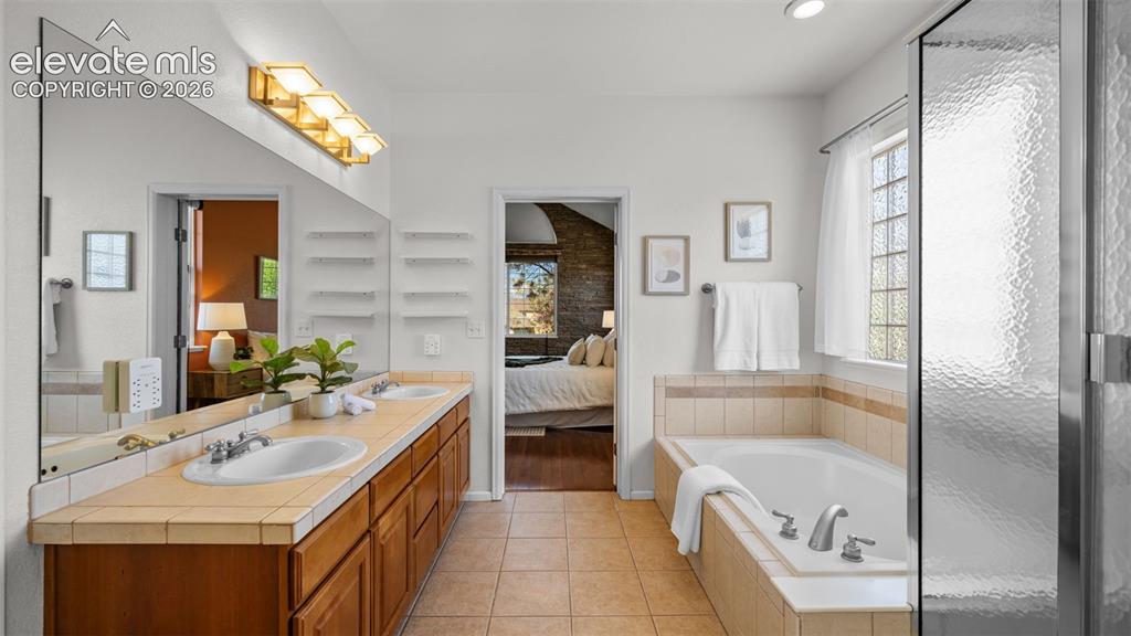 Image 15 of 43: Dual vanity with wood cabinetry and tile countertops
