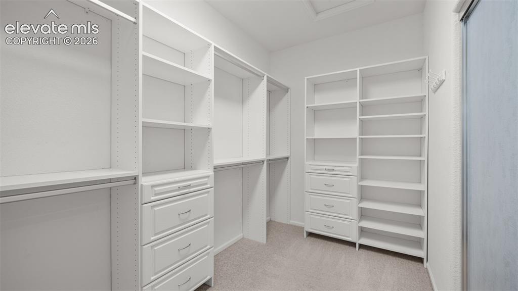 Image 16 of 43: Custom closet system featuring white cabinetry and shelving