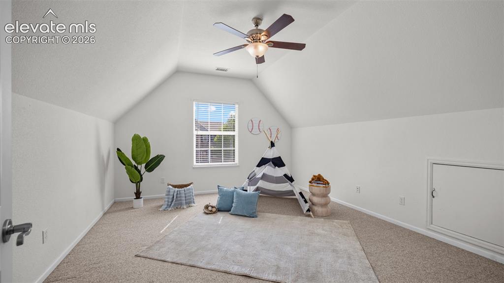 Image 24 of 43: Spacious room featuring vaulted ceilings, a ceiling fan with light fixture,
