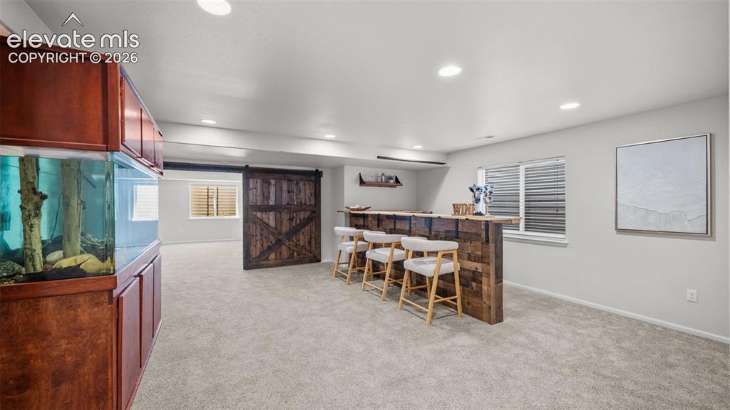 Image 28 of 43: Recessed lighting illuminates a built-in reclaimed wood-look bar with a woo
