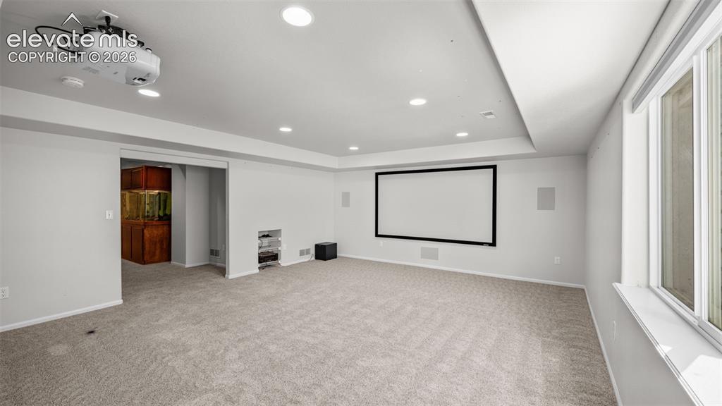 Image 30 of 43: Spacious entertainment room featuring recessed lighting, projector, built-i