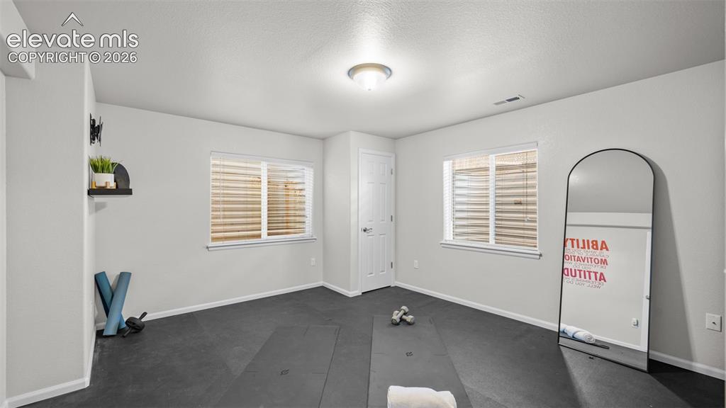 Image 31 of 43: Spacious room featuring durable rubber flooring, two windows with horizonta