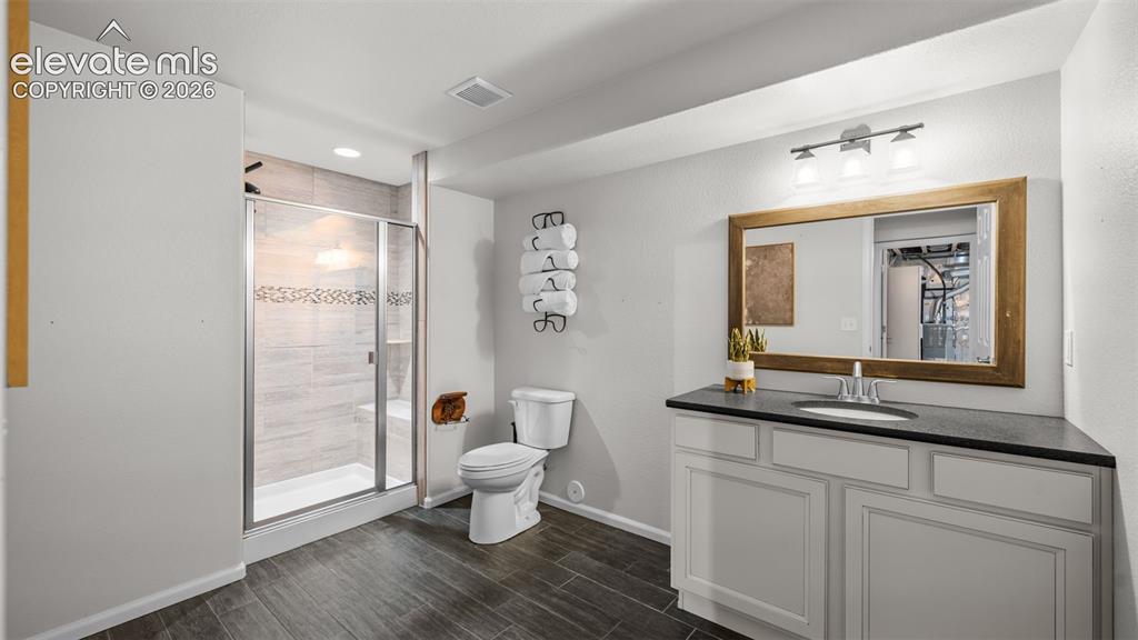 Image 32 of 43: Bathroom featuring a walk-in shower with glass enclosure, white vanity cabi