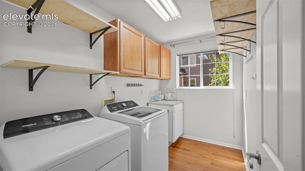 Image 35 of 43: Functional laundry area featuring wood-finish flooring, light wood cabinetr