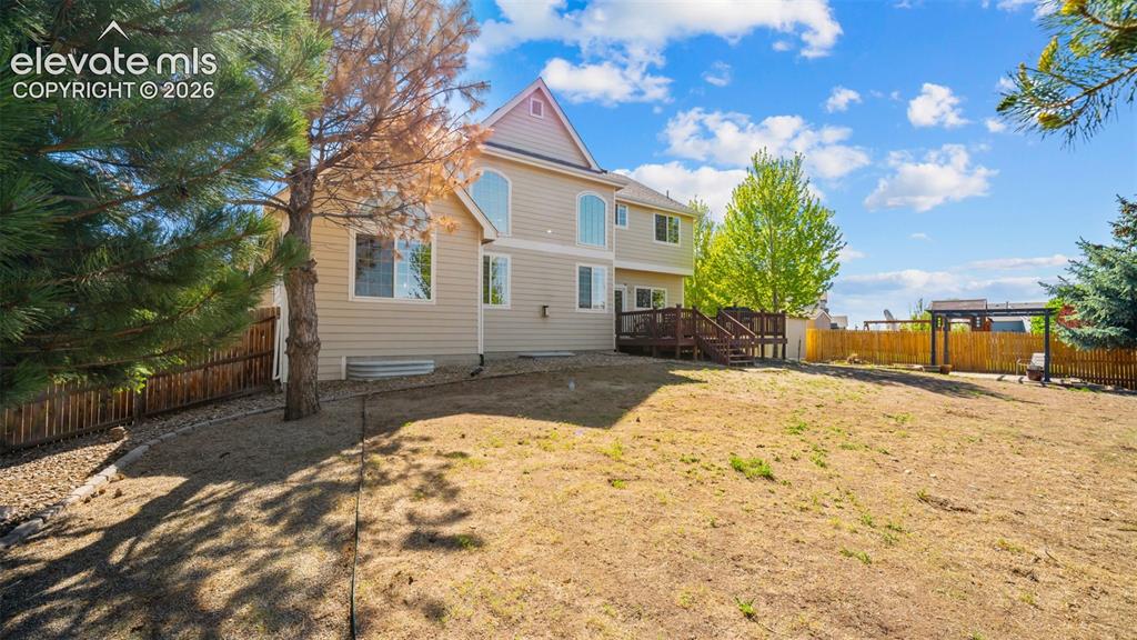 Image 37 of 43: Spacious backyard with a multi-level wood deck, expansive lawn, and partial