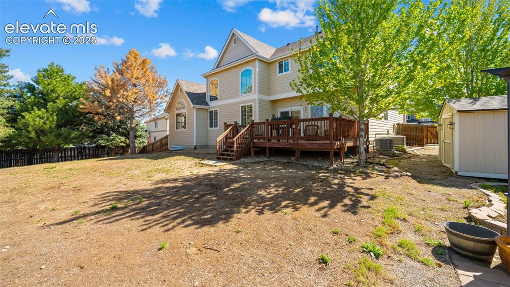 Image 38 of 43: Expansive backyard featuring a large wood-finish deck with stairs, a detach
