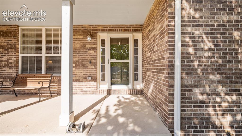 Image 4 of 43: Covered front porch featuring a brick exterior facade, white support column