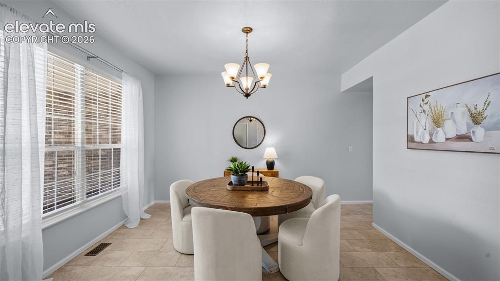 Image 6 of 43: Dining space featuring light wall tones, a large window, a bronze chandelie