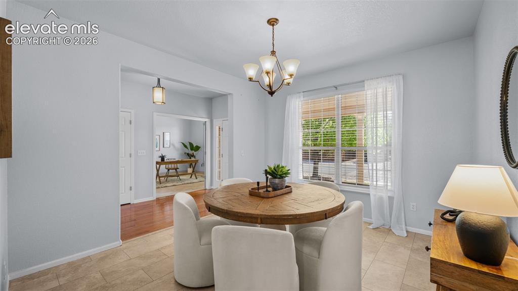 Image 7 of 43: Dining area featuring a circular wood-finish table, a bronze chandelier wit