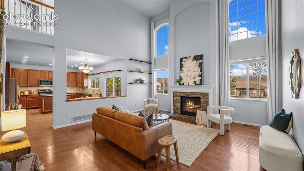 Image 9 of 43: Two-story living area with hardwood flooring, a brick fireplace, and floor-