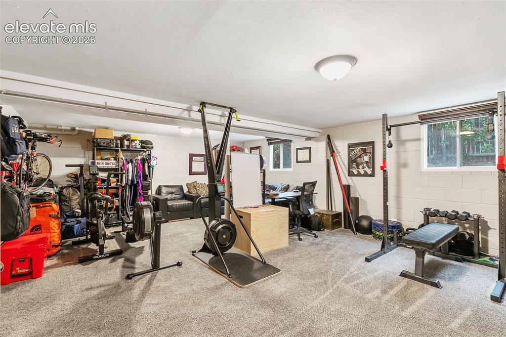 Image 27 of 39: Large basement family room, currently used as an office and home gym