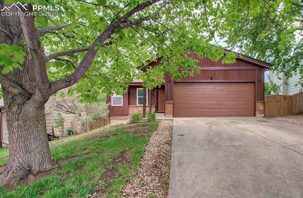 Caption: View of front of property with brick siding, a garage, and concrete driveway