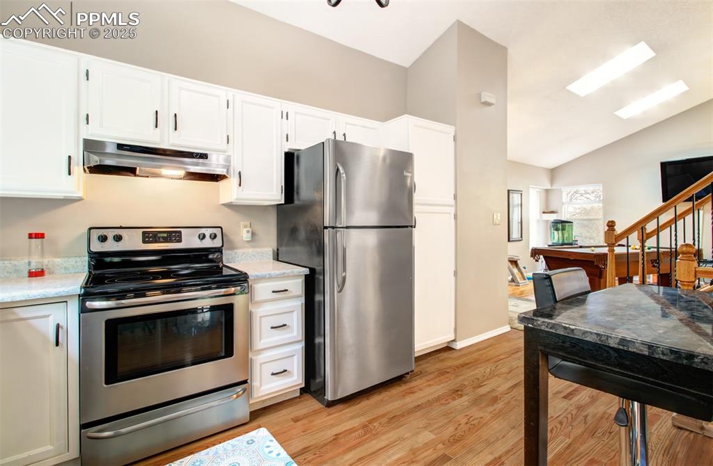 Image 10 of 25: Kitchen with under cabinet range hood, appliances with stainless steel fini