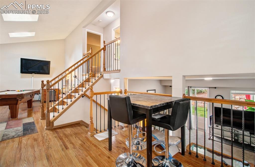 Image 11 of 25: Dining space featuring wood finished floors, high vaulted ceiling, a skylig