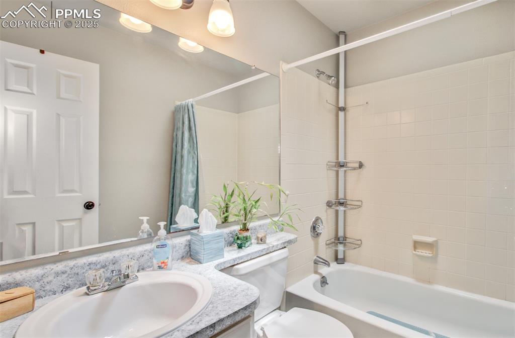 Image 14 of 25: Bathroom with shower / bath combo with shower curtain and vanity