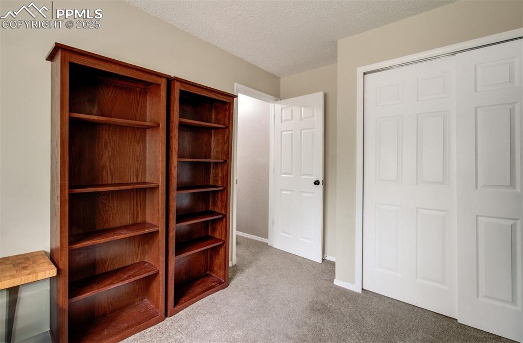 Image 21 of 25: Unfurnished bedroom with carpet floors, a textured ceiling, and a closet