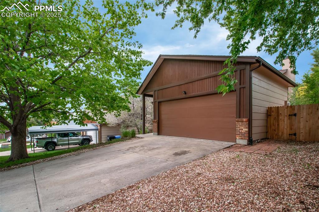 Image 24 of 25: View of front of home featuring concrete driveway, a chimney, and a garage