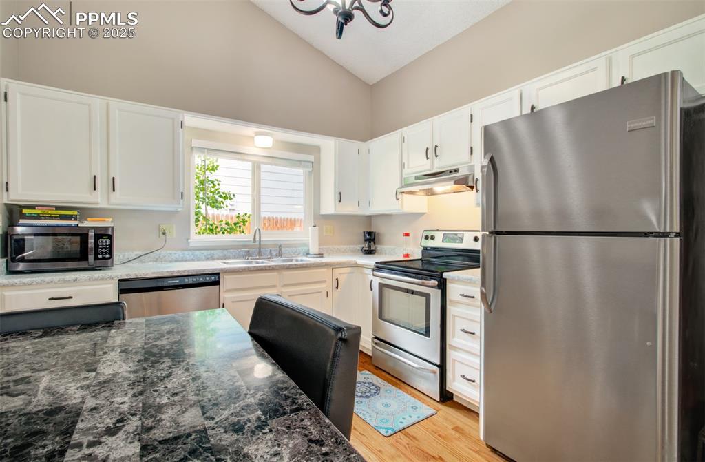 Image 5 of 25: Kitchen with stainless steel appliances, under cabinet range hood, high vau