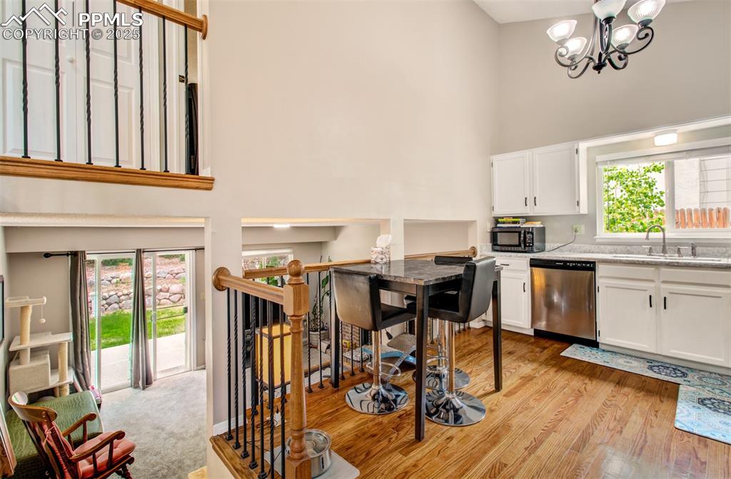 Image 9 of 25: Kitchen with dishwasher, a towering ceiling, light wood finished floors, wh