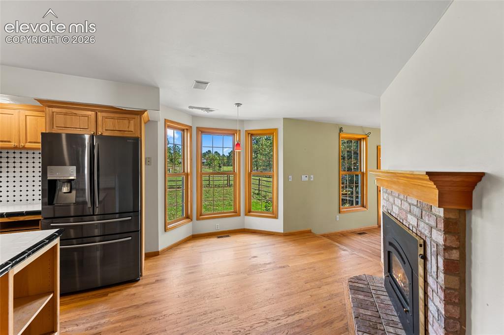 Image 12 of 49: Hardwood flooring throughout, brick fireplace with wood mantel, kitchen cab