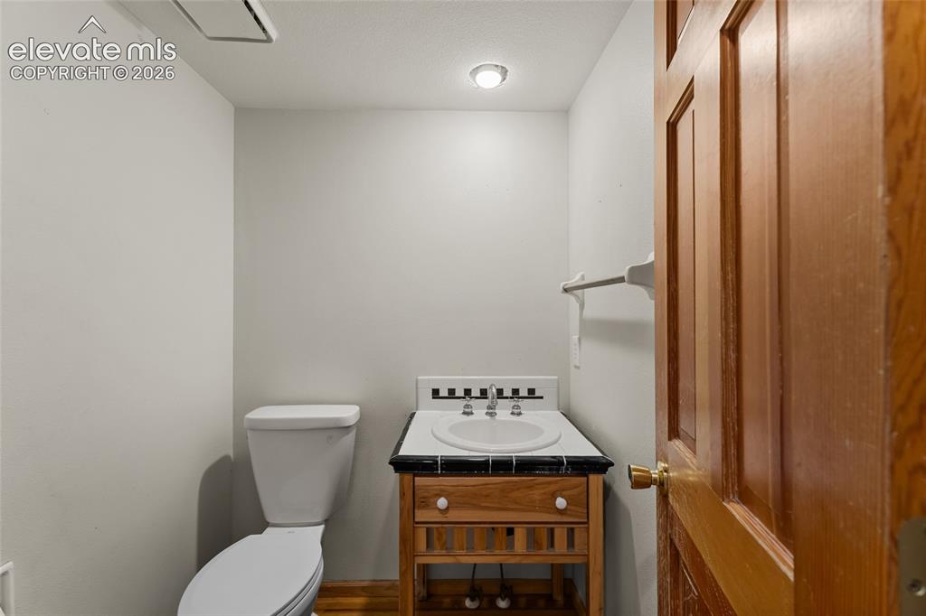 Image 16 of 49: Powder room featuring a pedestal toilet, wood vanity with an integrated sin
