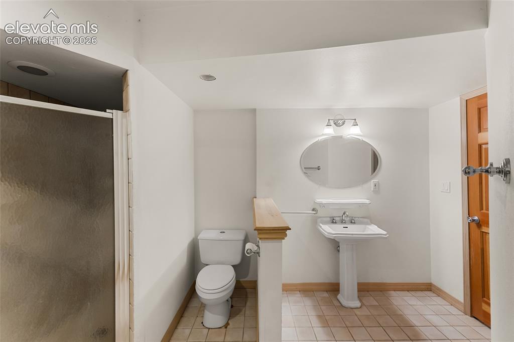 Image 25 of 49: Bathroom featuring a glass-enclosed shower, pedestal sink, oval vanity mirr