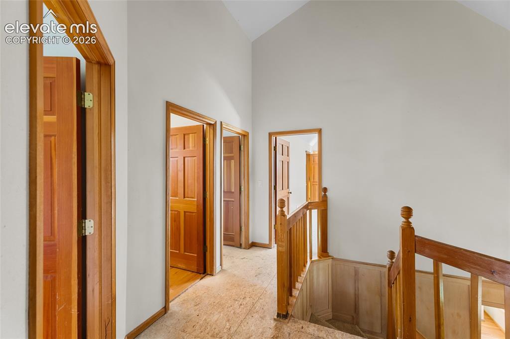 Image 27 of 49: Vaulted ceiling, natural wood doors, wood staircase, wood railing, and ligh