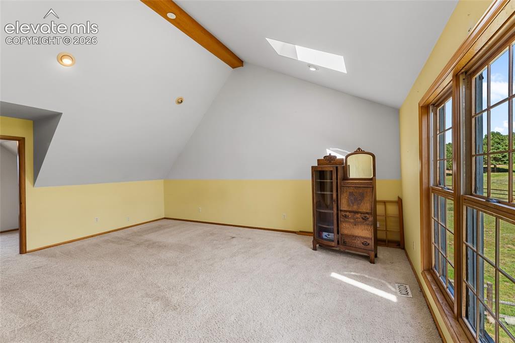 Image 28 of 49: Sloped ceiling with an exposed wood beam, recessed lighting, and a skylight