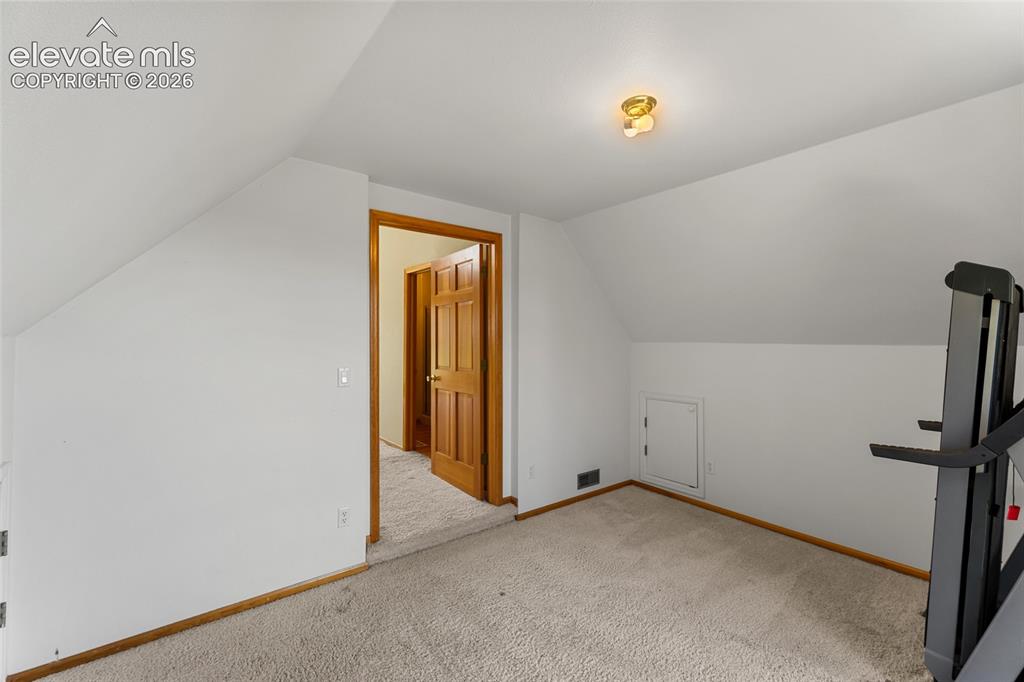 Image 32 of 49: Carpeted room with sloped ceilings and a flush-mount ceiling light