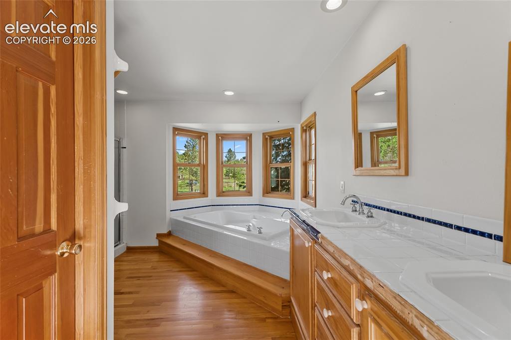 Image 34 of 49: Hardwood-finish flooring, built-in soaking tub with tiered wood-finish surr