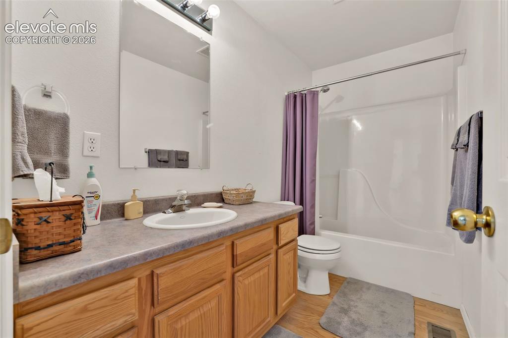 Image 37 of 49: Bathroom featuring a single vanity with wood-finish cabinetry, a built-in s