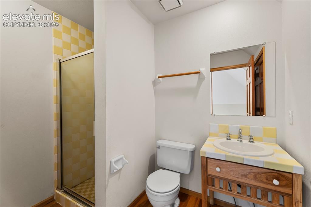 Image 38 of 49: Shower enclosure with checkered yellow and white tile, a built-in vanity wi