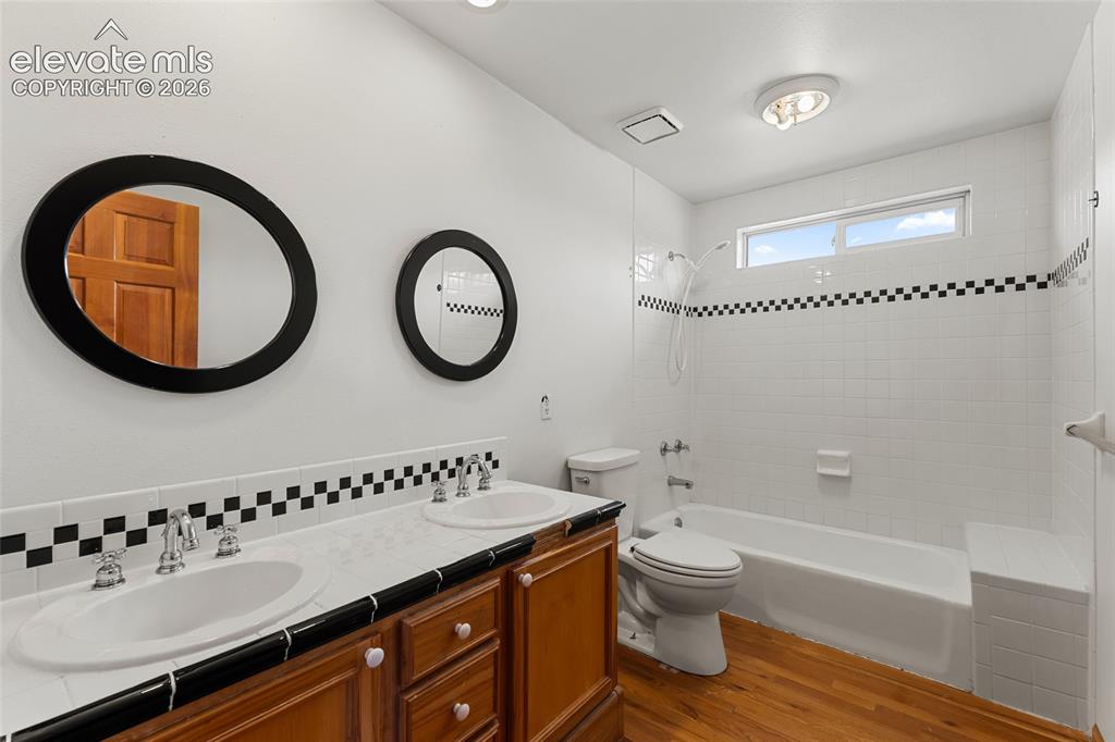 Image 41 of 49: Dual vanity with integrated sinks, wood-finish cabinetry, a built-in bathtu