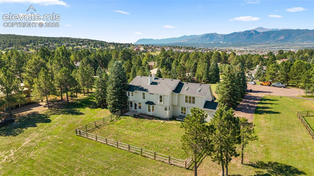 Image 45 of 49: Expansive property featuring a multi-story residence, mature trees, and a m